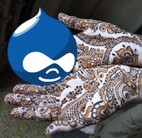 hands covered in henna patterns, holding the Drupal icon